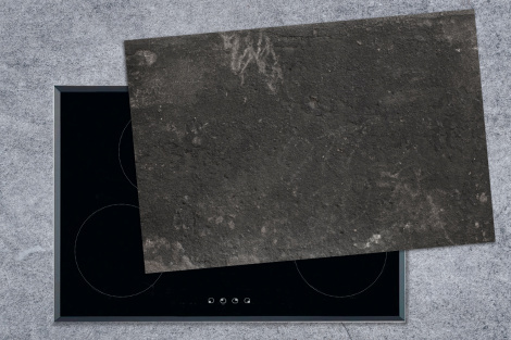 Inductie kookplaat beschermer zwartgrijze, betonnen muur met grijze vlekken